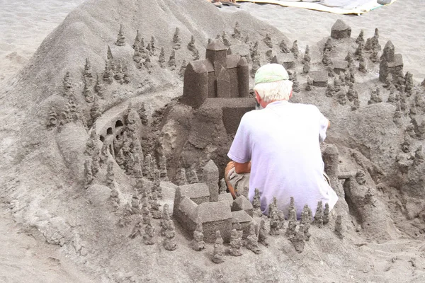 Yaşlı adam bina kum kale sahilde — Stok fotoğraf
