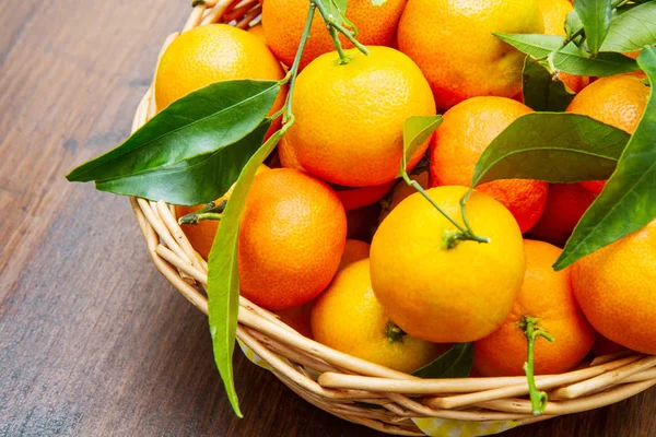 Fruta de mandarina fresca con hojas en la mesa de madera —  Fotos de Stock