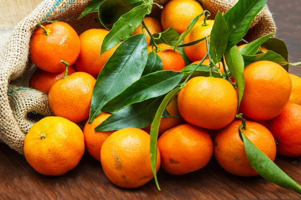 Свежие апельсины с листьями на деревянном столе — стоковое фото