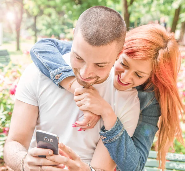 Giovane coppia con cellulare al parco — Foto Stock