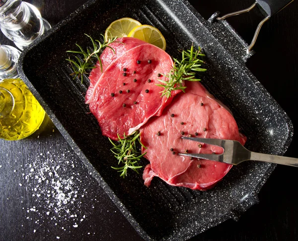 검은 배경에 접시 냄비에 원시 썬된 쇠고기 — 스톡 사진