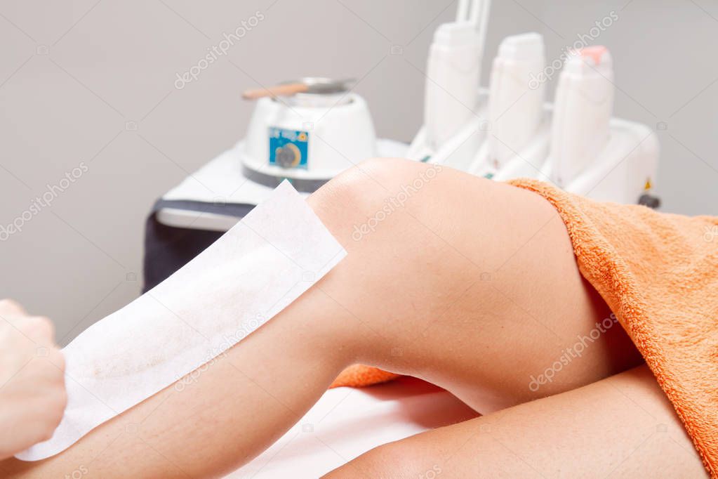 Beautician waxing a woman's leg 