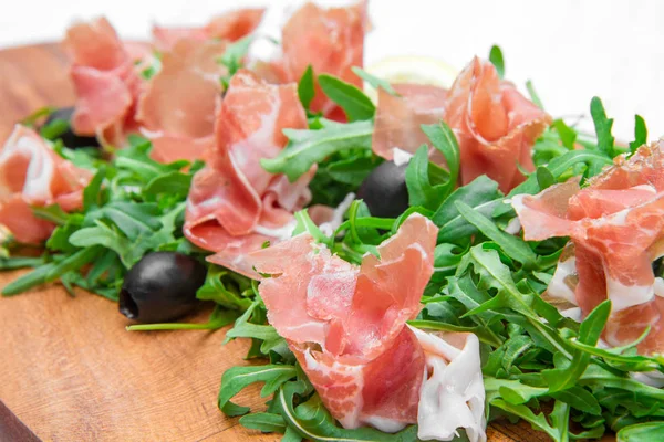 Chopping board with aragula and raw ham — Stock Photo, Image