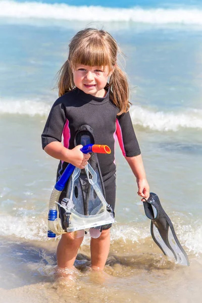 Happy girl on beach with colorful face masks and snorkels, sea i — Stock Photo, Image