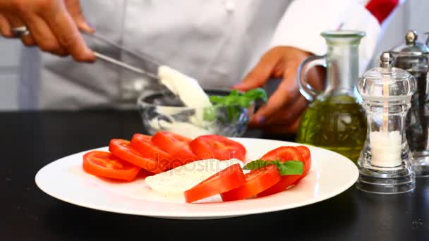 Профессиональный повар готовит тарелку со свежими помидорами и моцареллой — стоковое видео