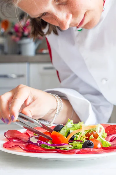 Chef che prepara piatti con bersaola e insalata mista — Foto Stock