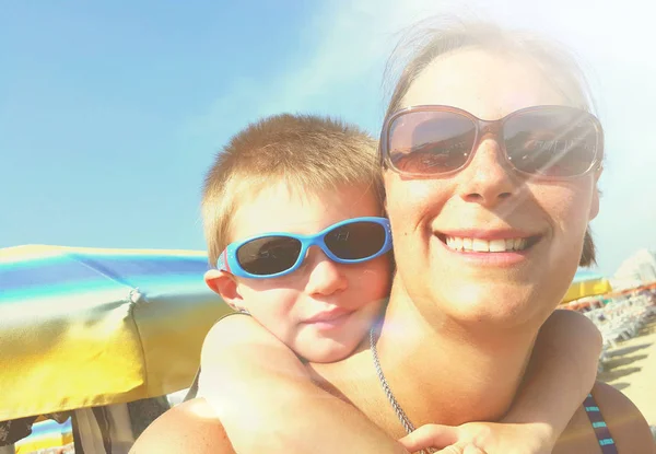 Mamá y su hijo sonríen felices en la playa — Foto de Stock