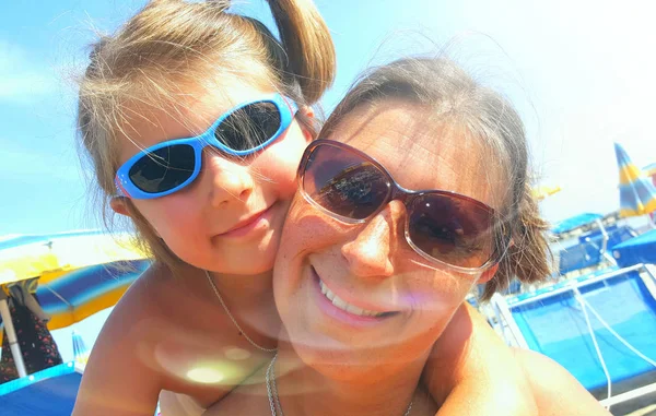 Mamá y su hija sonríen felices en la playa — Foto de Stock