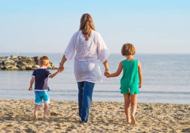 Anne ve çocukları sahilde el ele yürümek 
