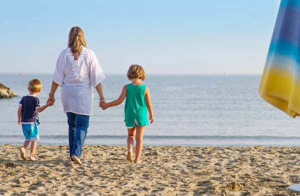 Mutter und Kinder gehen Hand in Hand am Strand — Stockfoto