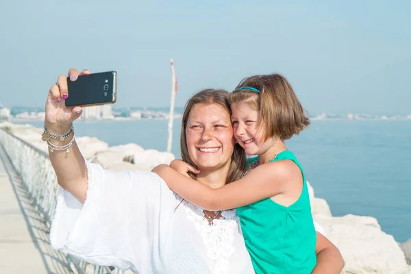 Мама и дочь фотографируют улыбаясь — стоковое фото