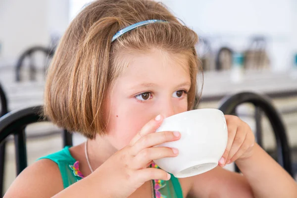 Meisje, drinken een kopje melk bij het ontbijt — Stockfoto