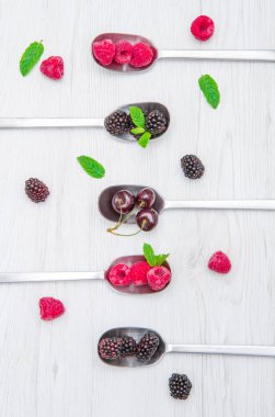 Beyaz ahşap zemin üzerinde çelik kaşık üzerinde taze çilek