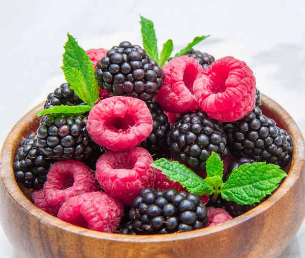 Wooden cup with fresh berries on white marble background — Stock Photo, Image