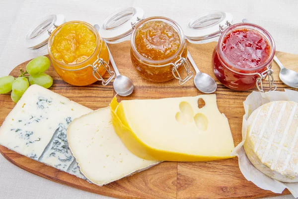 Tabla de cortar de madera con queso y mermeladas — Foto de Stock