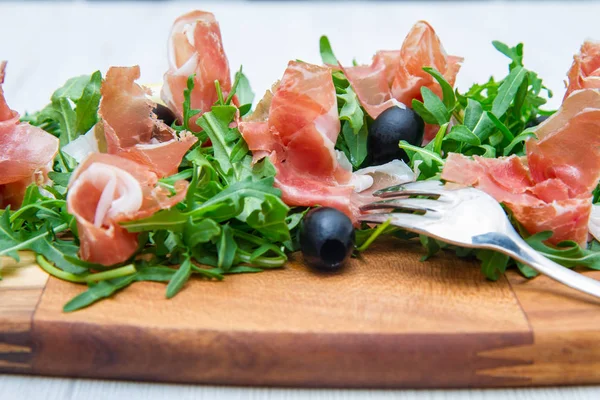 Chopping board with aragula and raw ham — Stock Photo, Image