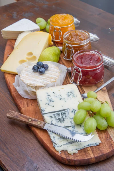 Tabla de cortar de madera con queso y mermeladas — Foto de Stock