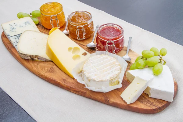 Tabla de cortar de madera con queso y mermeladas — Foto de Stock