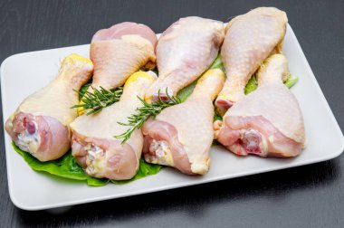 siyah ahşap masa üzerinde beyaz bir tabak tavuk uyluk