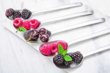 Beyaz mermer zemin üzerine çelik kaşık üzerinde taze çilek 