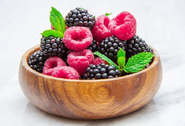 Tazza di legno con bacche fresche su sfondo di marmo bianco — Foto Stock