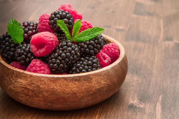 Деревянная чашка со свежими ягодами на деревянном столе — стоковое фото