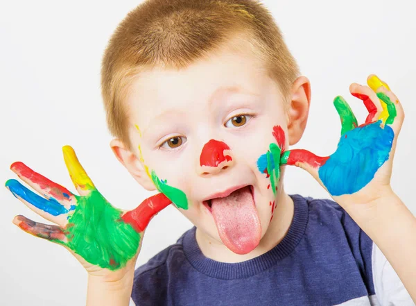 Lächelnder kleiner Junge mit in bunten Farben bemalten Händen — Stockfoto
