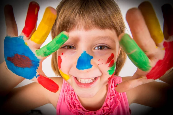 Niña sonriente con las manos pintadas en pinturas de colores — Foto de Stock