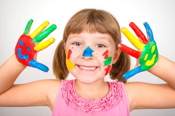 Menina sorridente com as mãos pintadas em tintas coloridas — Fotografia de Stock
