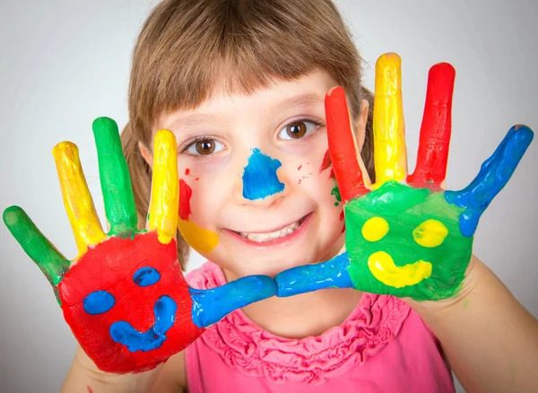 Lächelndes kleines Mädchen mit in bunten Farben bemalten Händen — Stockfoto