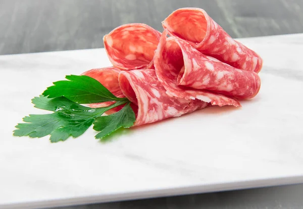 Marble dish with salami slices — Stock Photo, Image