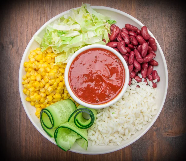 Веганское блюдо с рисом, красной фасолью, кукурузой и огурцом — стоковое фото