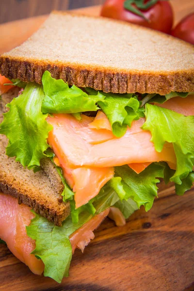 Сэндвич с копченым лососём, салатом и лимоном — стоковое фото