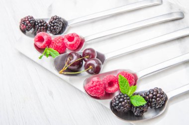 Beyaz mermer zemin üzerine çelik kaşık üzerinde taze çilek 