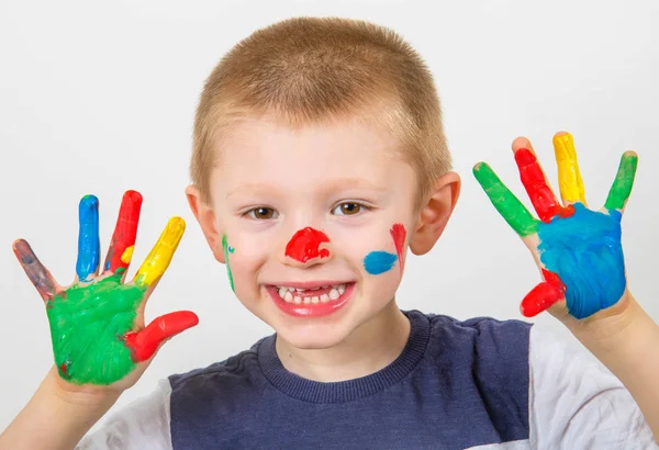 Menino sorrindo com as mãos pintadas em tintas coloridas — Fotografia de Stock