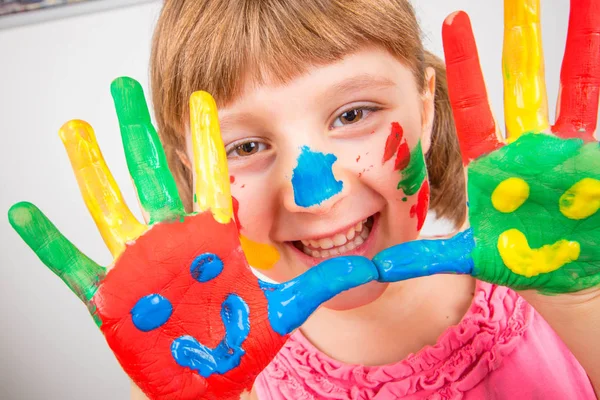Lächelndes kleines Mädchen mit in bunten Farben bemalten Händen — Stockfoto