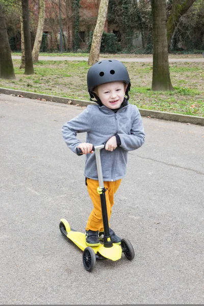 Menino com scooter amarelo no parque — Fotografia de Stock