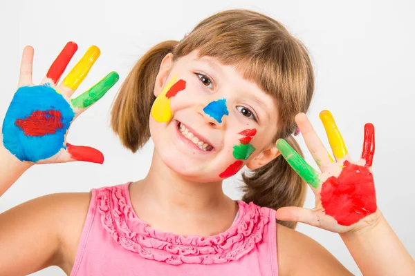 Menina sorridente com as mãos pintadas em tintas coloridas — Fotografia de Stock