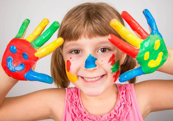 Menina sorridente com as mãos pintadas em tintas coloridas — Fotografia de Stock