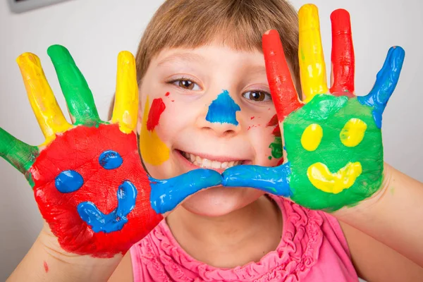 Smiling little girl with hands painted in colorful paints — Stock Photo, Image