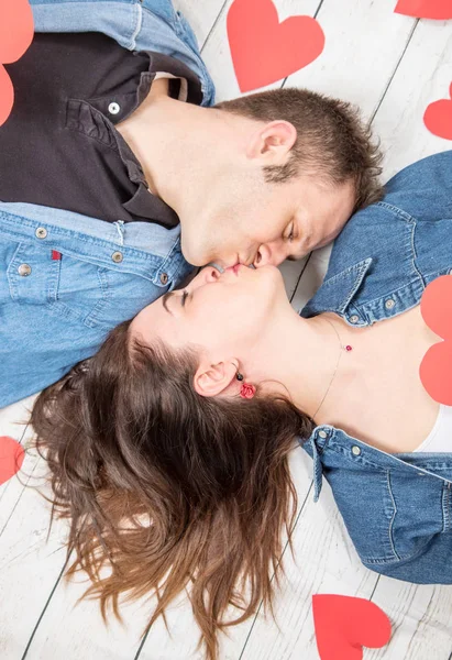 Pareja acostada en el suelo de madera con corazones —  Fotos de Stock