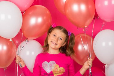Renkli balonları olan güzel bir kız. Pembe sırt çantasına gülümsüyor.