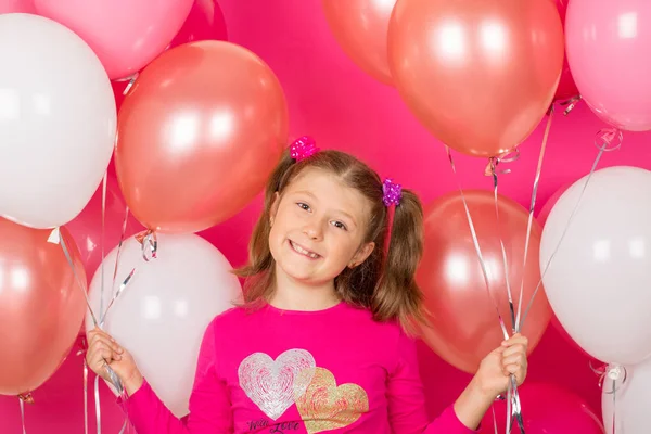 Renkli balonları olan güzel bir kız. Pembe sırt çantasına gülümsüyor.