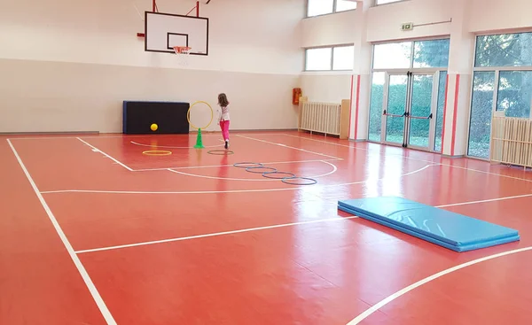 Chica joven está haciendo ejercicio en una escuela primaria gimnasio interior — Foto de Stock