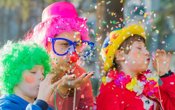 Una madre y sus hijos están jugando con confeti en el carnaval — Foto de Stock