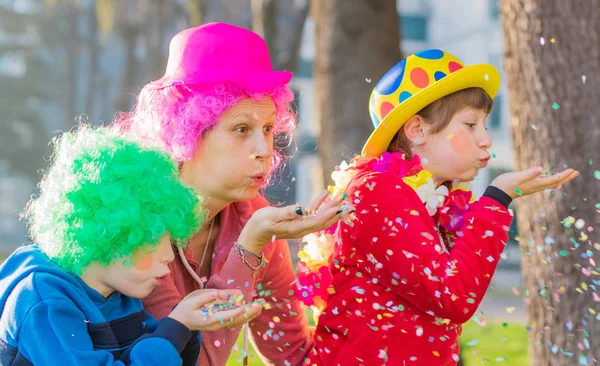 Een moeder en haar kinderen spelen met confetti in carnaval — Stockfoto