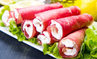 Beyaz tabakta kurutulmuş et ve peynir.