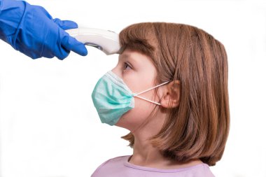 Çocuk doktoru ya da doktor, ilkokul çağındaki kızın vücut ısısını virüs belirtileri için kızılötesi alın termometresi (termometre tabancası) kullanarak kontrol eder - salgın koronavirüs salgını kavramı