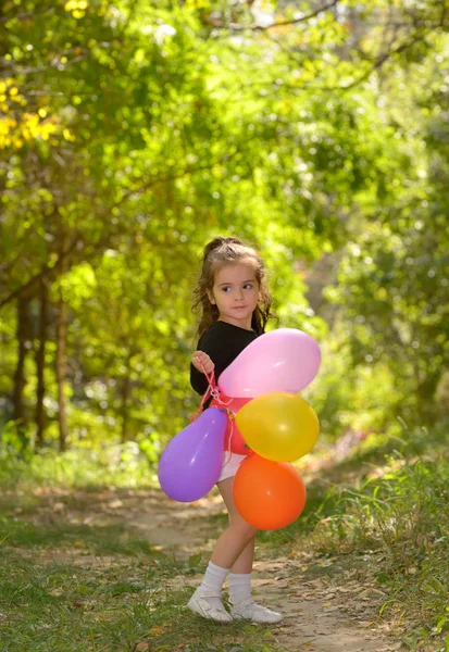 Liten flicka med färgglada ballonger — Stockfoto