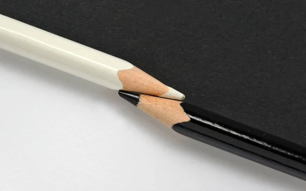 Crayons noirs et blancs sur le même fond de papier — Photo